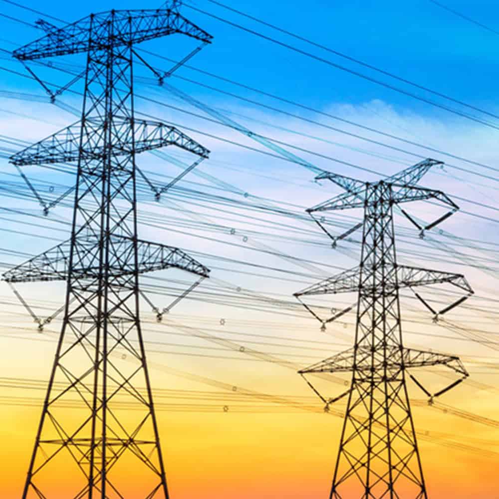 High voltage power transmission towers against sunset sky.