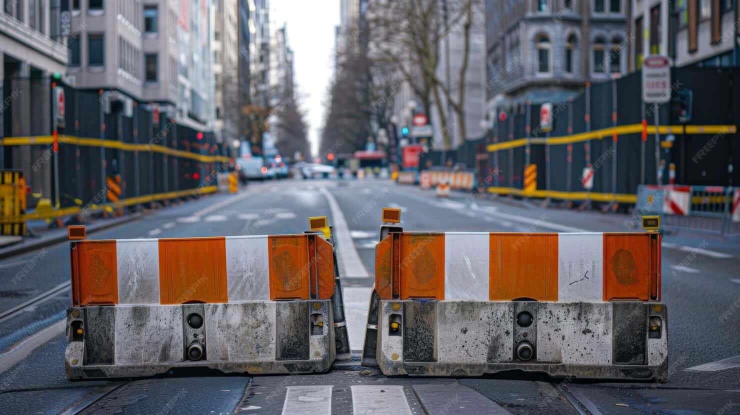 Temporary orange and white road barricades blocking a city street for construction.