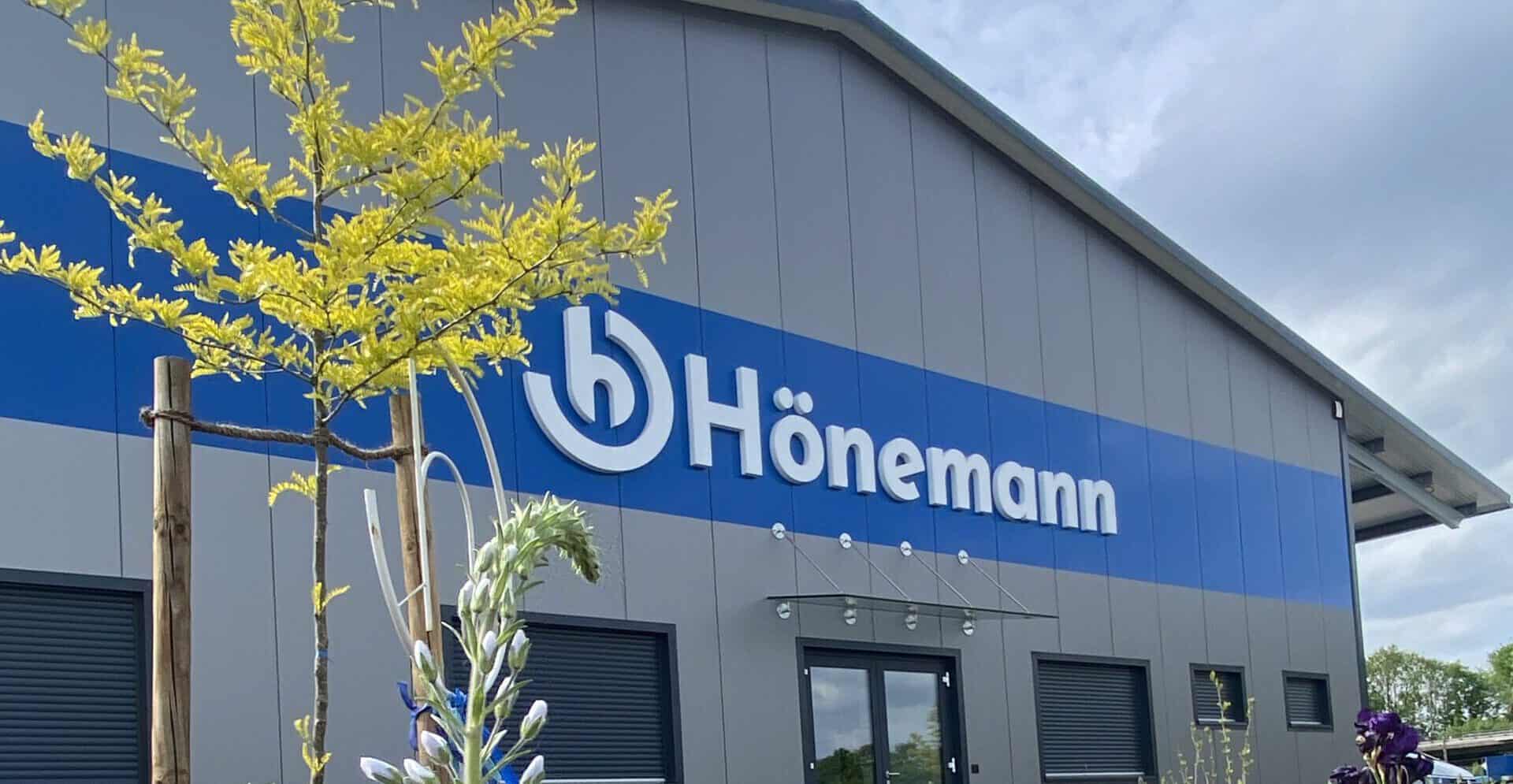 Firmengebäude der Hönemann GmbH mit moderner Fassade und Firmenlogo am Eingangsbereich.
