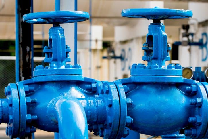 Mehrere blaue Wasserpumpen mit angeschlossenen Hähnen in technischer Umgebung.