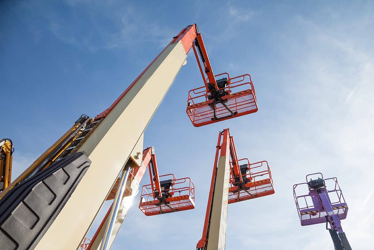 Mehrere Gelenkteleskoparbeitsbühnen mit ausgefahrenen Armen, die hoch in den Himmel ragen.