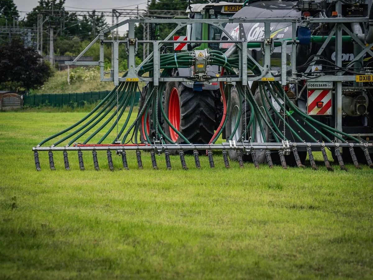 Dribble bar close up Tractor with slurry injector on green field