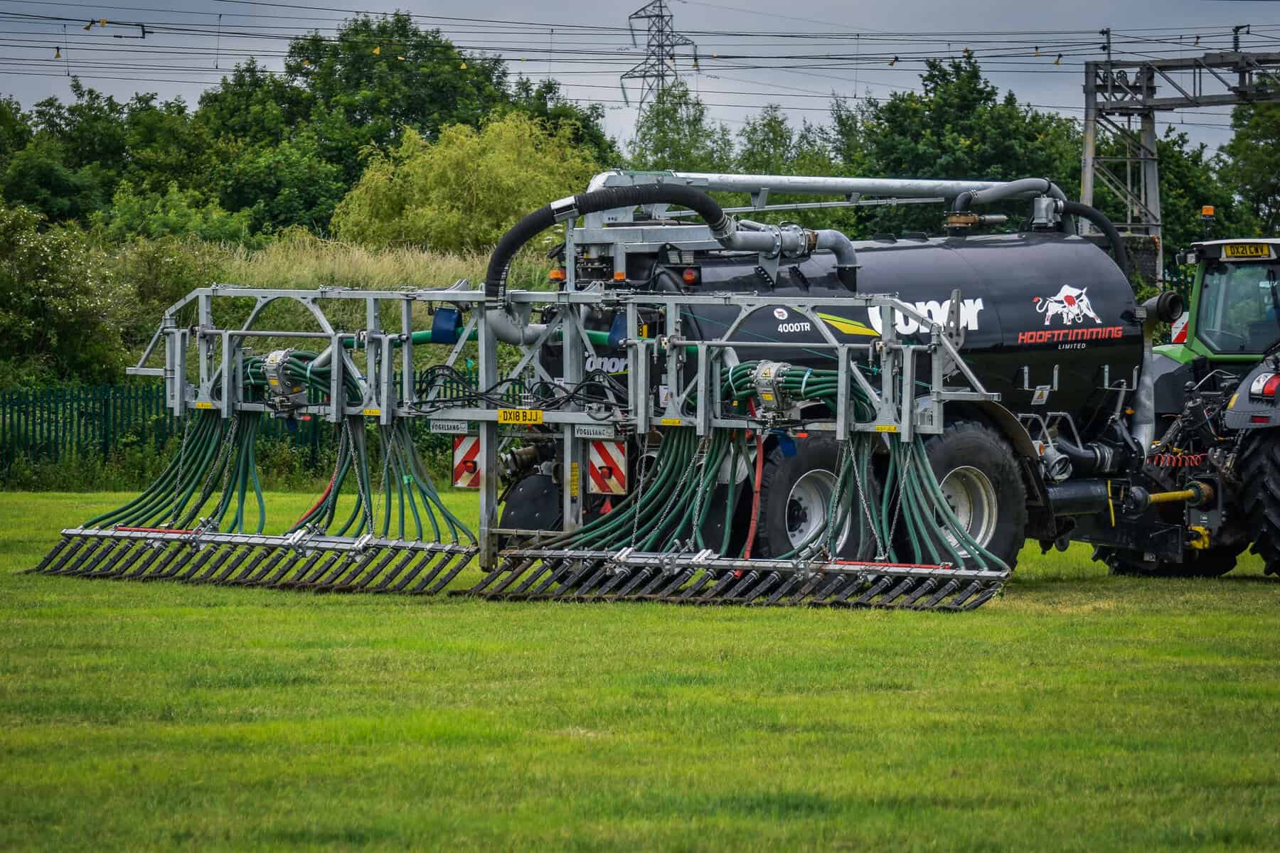 Agricultural machine spreading fertilizer on grass field.