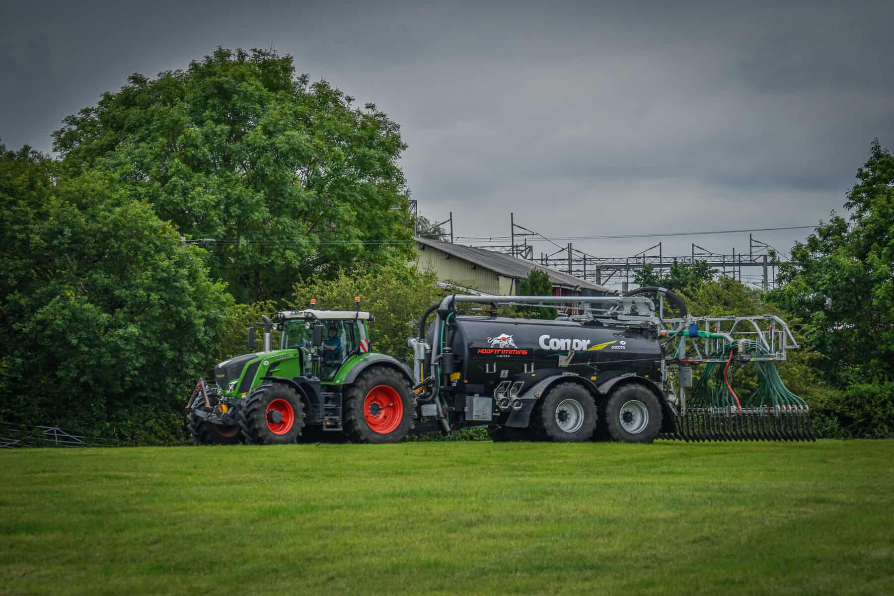 Tractor pulling large agricultural machine on field.