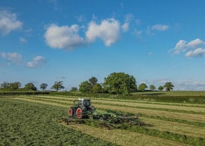 Tractor mowing grass in a large green field.