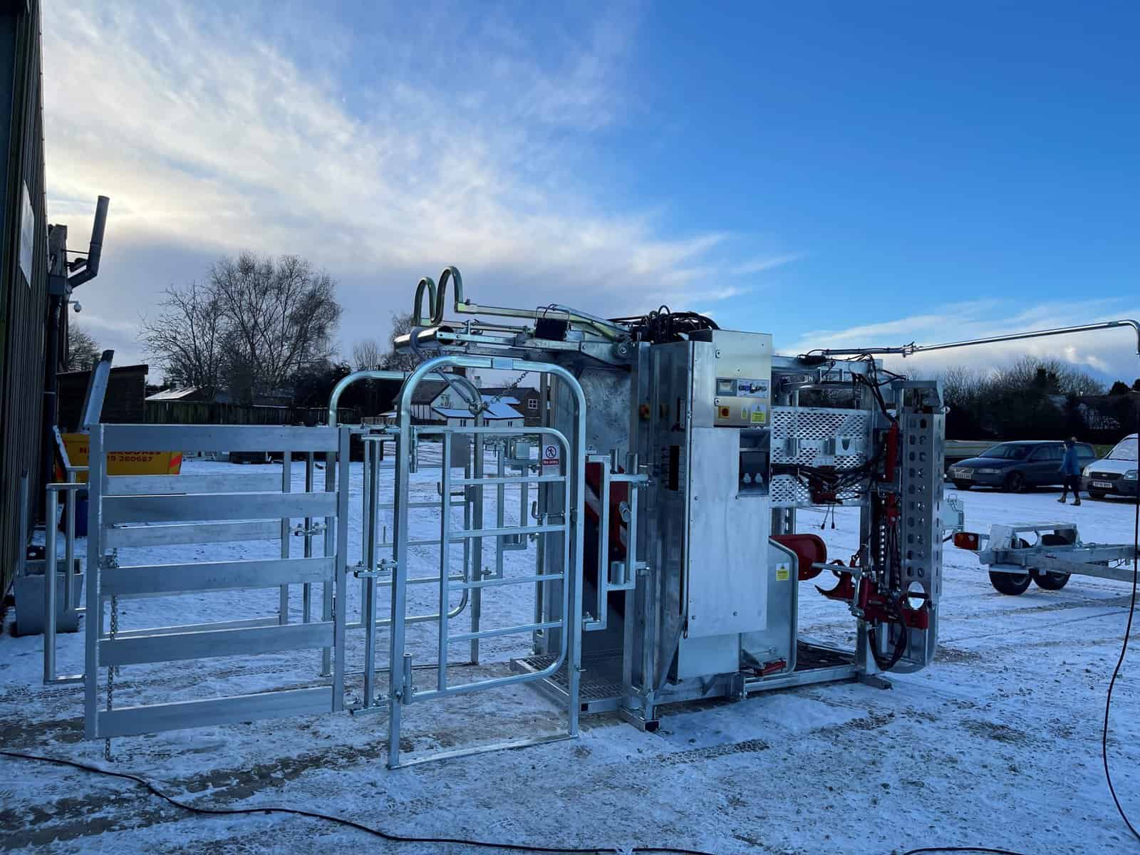 Livestock handling equipment on snowy farm landscape.