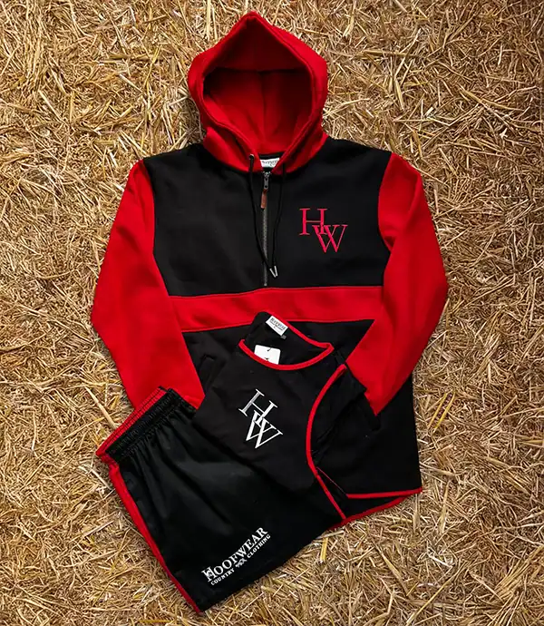 Red and black hoodie and shorts on straw background.