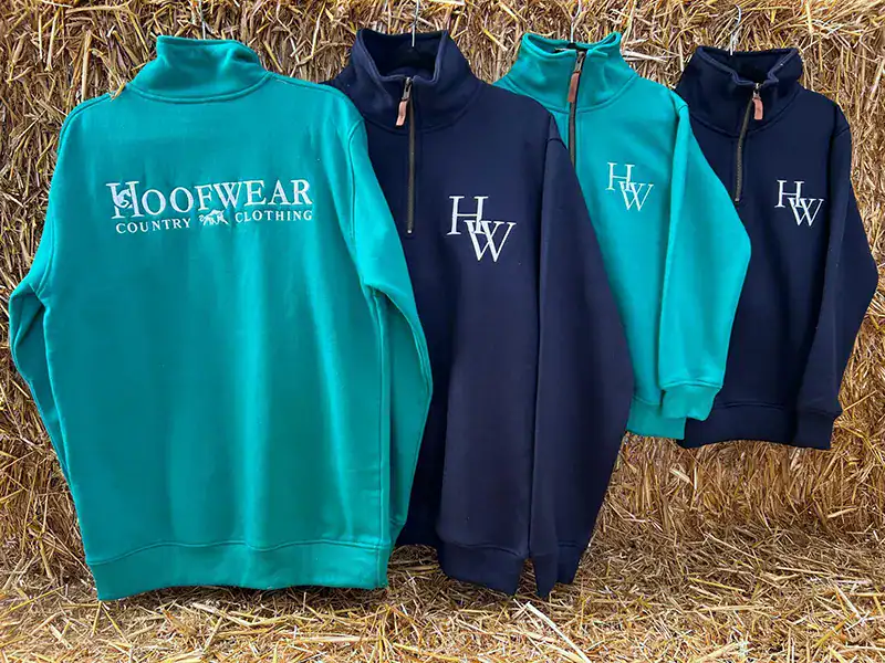 Four country clothing sweatshirts on hay backdrop.