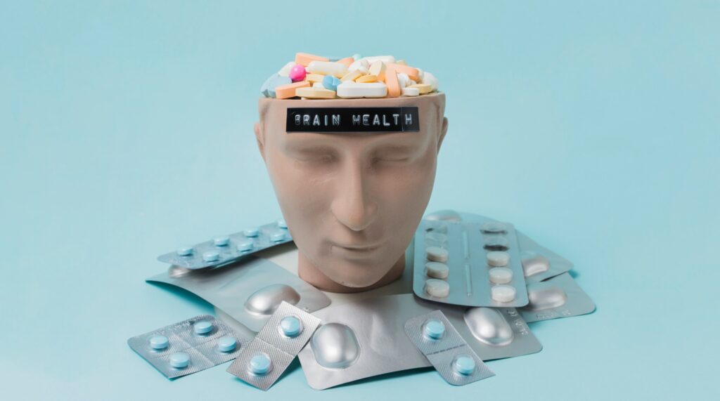 Pills and medication surrounding a mannequin head with a label "brain health" on the forehead, symbolizing mental health treatment, medication management, and wellness support by Hope Again Wellness Center.