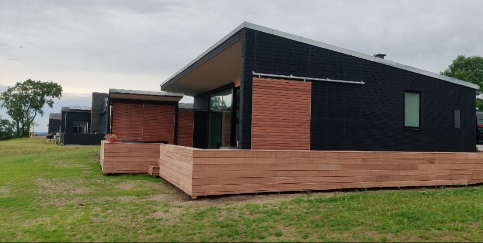 Moderne bygning med rød murstensfacade og sortmalet træbeklædning.