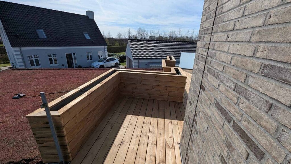 Tagterrasse bygget i træ med udsigt over omkringliggende huse.