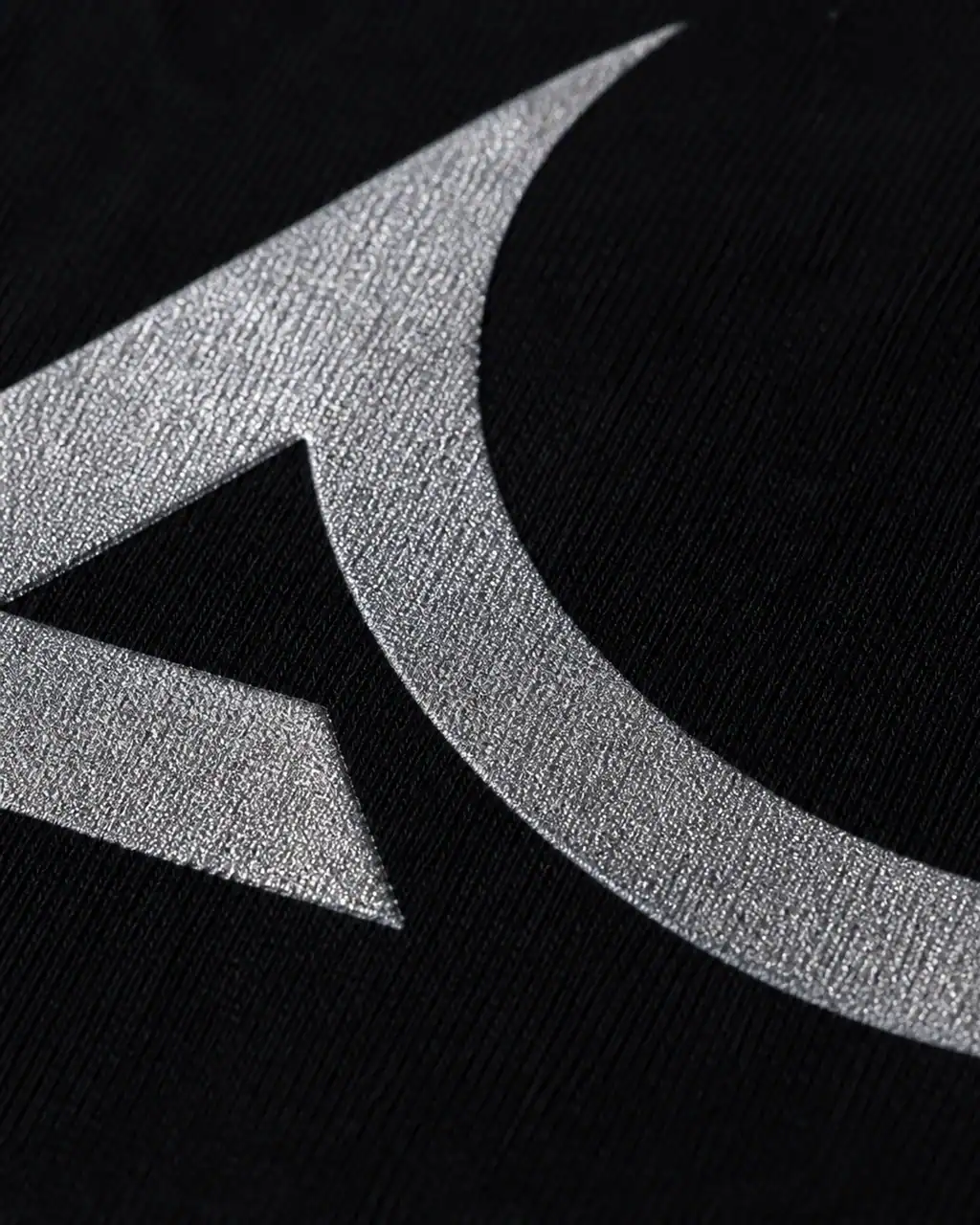 Macro close-up of shimmering silver metallic ink on black fabric showing the fine flakes