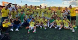 Jugadores y cuerpo técnico posan felices con uniforme amarillo y azul, mostrando entusiasmo y espíritu deportivo.