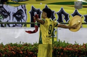 Atlético Huila celebra en el campo tras una goleada en casa, liderando el grupo B en la Primera B. El jugador muestra entusiasmo y orgullo por el triunfo frente a Cúcuta.
