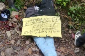 Cadáver con mensaje de las disidencias de las FARC-EP en Planadas, Colombia, mostrando un cuerpo sin vida en un entorno natural con una nota escrita a mano.