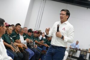 1. Hombre dando conferencia en evento Huila TV con audiencia diversa en sala moderna, énfasis en comunicación y medios de comunicación en el departamento de Huila.