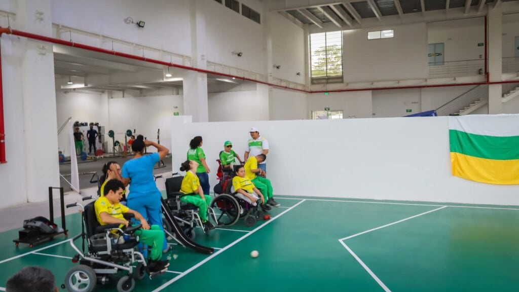 Estudiantes en wheelchairs participando en actividad deportiva en interior de gimnasio en Huila Tv, Colombia.