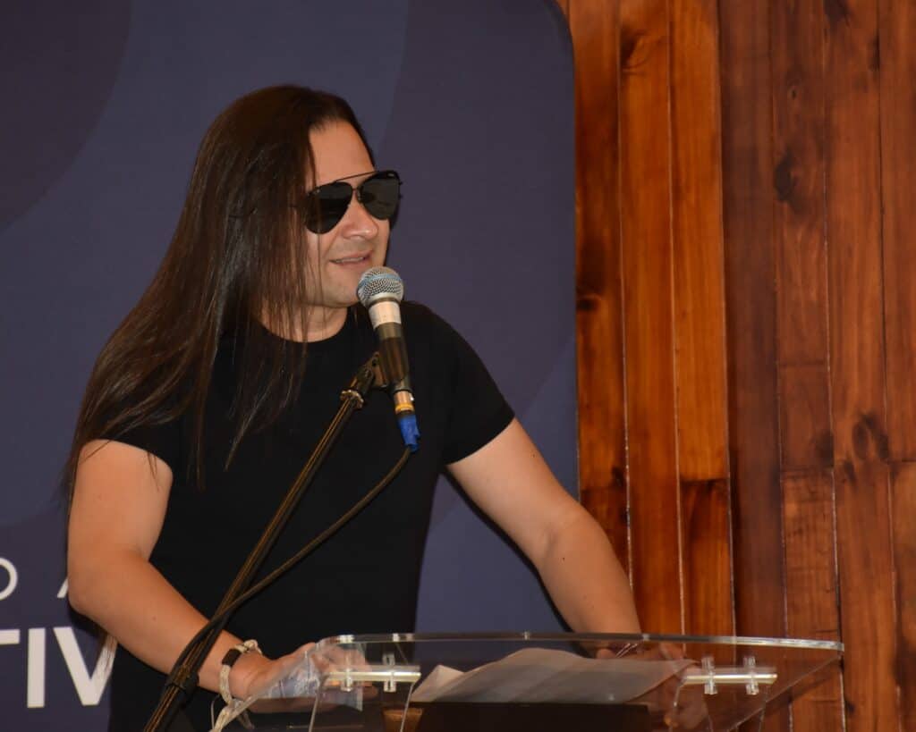 Discurso en vivo en Huila TV con persona usando gafas de sol negras en un evento en un estudio con paredes de madera.