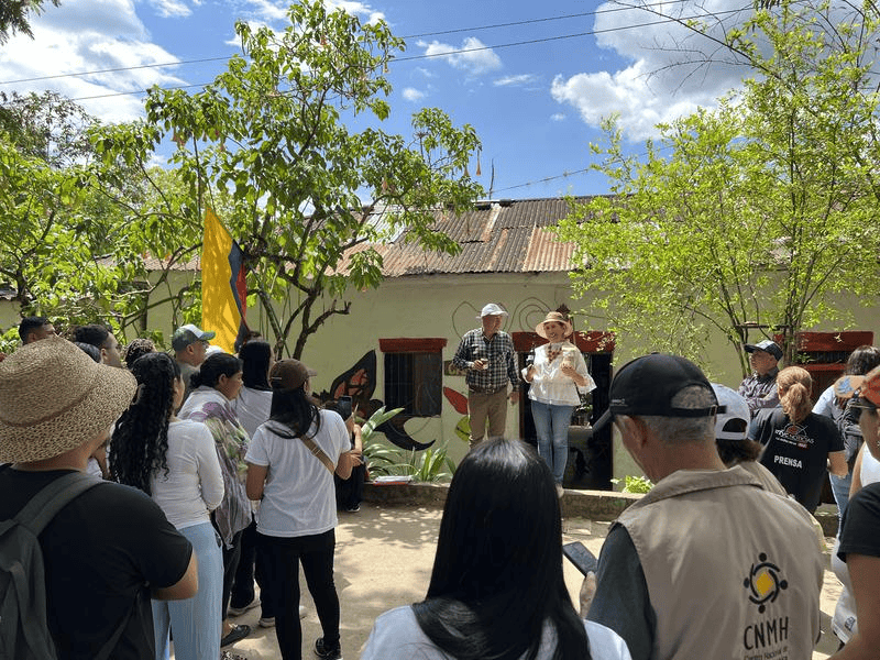 1. Personas participando en evento cultural en Huila, Colombia, en un día soleado, con árboles verdes y cielo azul.