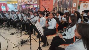 1. Banda de orquesta en vivo en Huila TV, mostrando músicos tocando instrumentos en un evento cultural en un centro comercial.