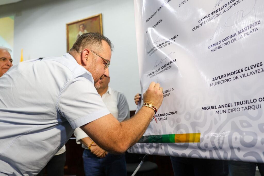 1. Hombre firmando un acuerdo oficial en una ceremonia en Huila TV, evento destacado de noticias y cultura en el departamento de Huila, Colombia.