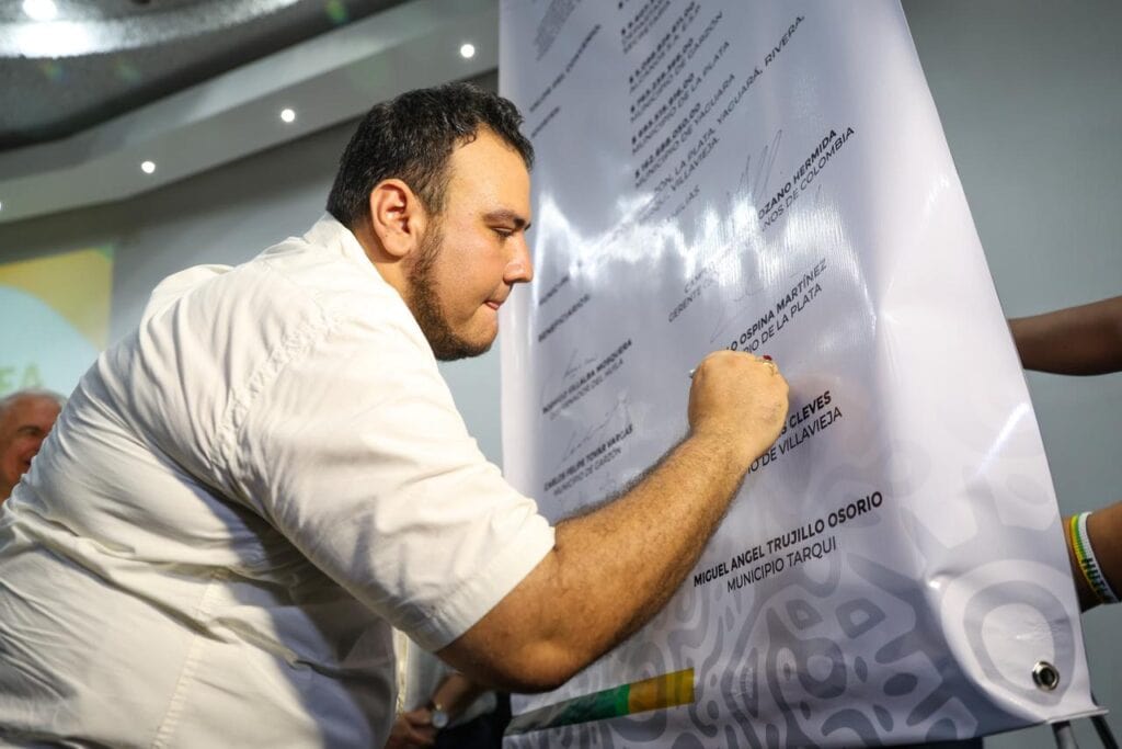 1. Persona firmando un documento oficial en un evento público en Huila, Colombia, mostrando participación ciudadana y compromiso cívico en el departamento del Huila.