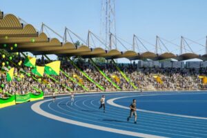 Atletismo en estadio de Huila Tv con espectadores, banderas y ambiente deportivo vibrante en Colombia.