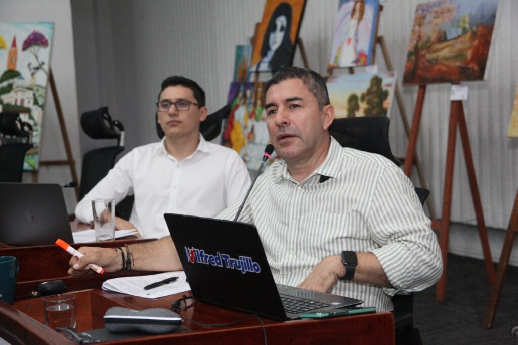 1. Imagen de dos hombres en reunión en Huila TV con obras de arte en el fondo, promoviendo cultura y arte en el departamento de Huila.