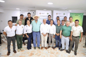 1. Grupo de personas en una reunión oficial en Huila, Colombia, con fondo de carteles y banner institucional, durante un evento de Huila TV.