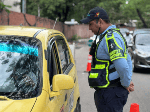 1. Agente de tránsito inspeccionando un taxi amarillo en vía pública, cumpliendo con regulaciones de transporte en Huila, Colombia.