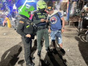 Policías en Huila Tv revisando información en un teléfono móvil en un ambiente nocturno en un evento público de la región.