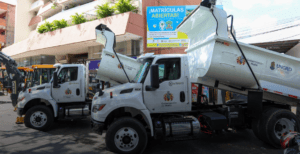 Policía de basura en Huila, Colombia, recolectando residuos en vehículos oficiales con logotipos de la Gobernación del Huila y UNGRD, promoviendo gestión ambiental y limpieza urbana.