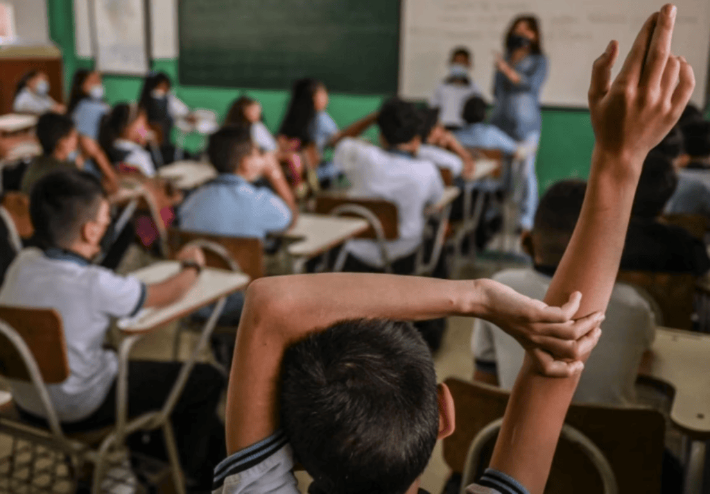 Estudiantes en aula escolar en Huila, participando en clase con un maestro en un entorno educativo. La imagen refleja el compromiso de Huila con la educación y la matrícula escolar en 2026.
