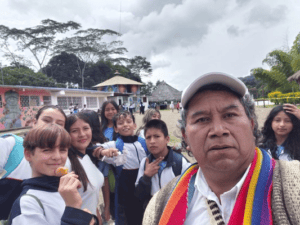 Estudiantes indígenas en San Agustín con su maestro, en un entorno escolar rodeado de naturaleza, promoviendo la educación inclusiva y cultural en la región del Huila.