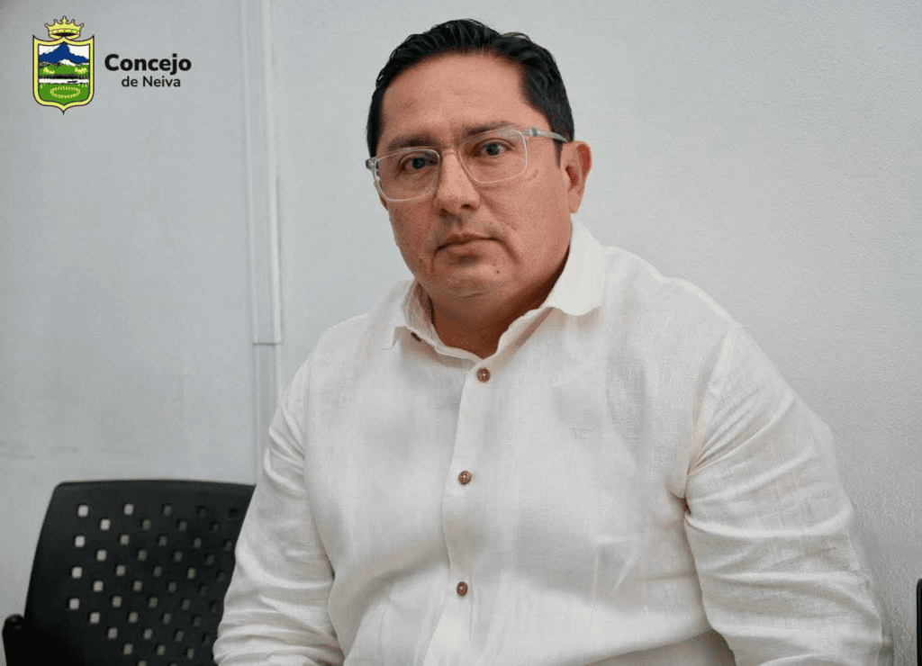 Joven con expresión seria en un incidente en Algeciras, cerca de una ambulancia y personal de emergencia en un lugar con señalización de urgencias.