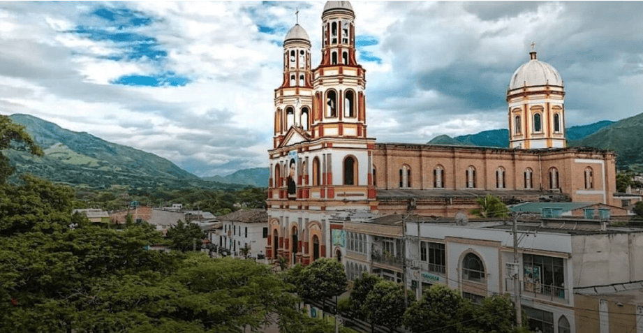 Vista panorámica de la iglesia en La Plata, Huila, Colombia, con montañas y cielo nublado en el fondo.
