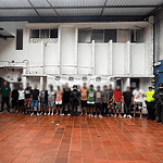 Personas detenidas en una estación de policía en Huila, Colombia, rodeadas por oficiales de seguridad en un ambiente cerrado y vigilado.