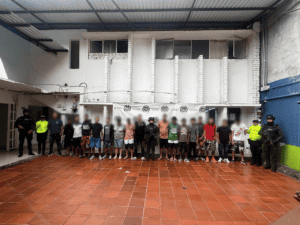 Personas detenidas en una estación de policía en Huila, Colombia, rodeadas por oficiales de seguridad en un ambiente cerrado y vigilado.