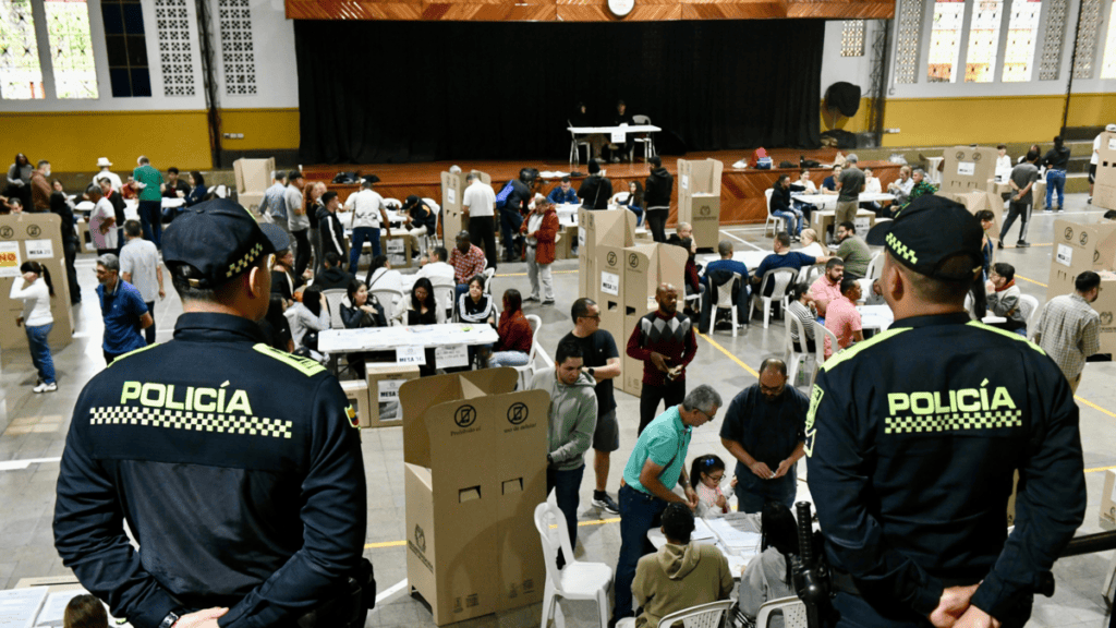 Huila Tv, evento comunitario con presencia policial en un espacio cerrado, donde se observa a varias personas participando en actividades y revisando productos en un ambiente seguro y organizado.
