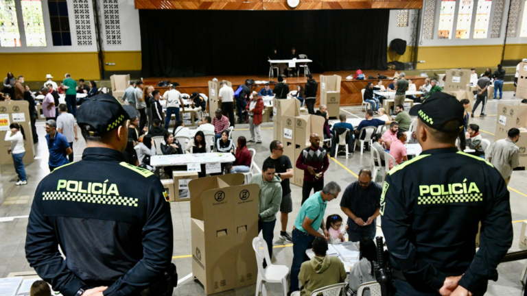 Huila Tv, evento comunitario con presencia policial en un espacio cerrado, donde se observa a varias personas participando en actividades y revisando productos en un ambiente seguro y organizado.