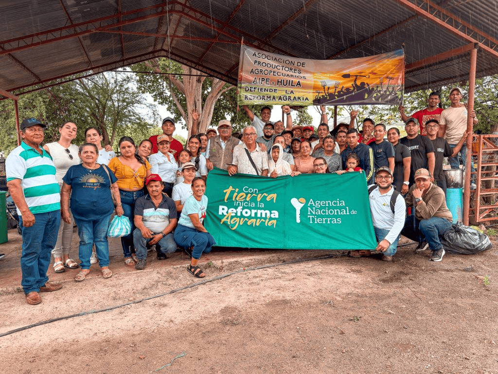 Grupo de agricultores y productores rurales en Huila participando en evento de reforma agraria y agricultura sostenible en un espacio al aire libre con banners informativos.