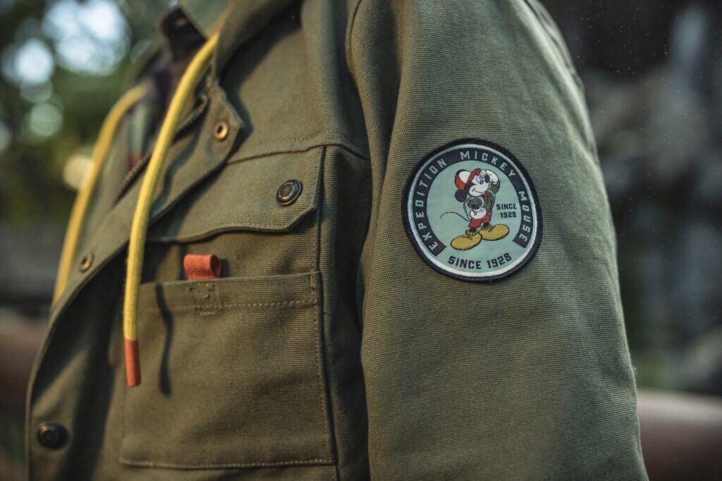 Embroidered Mickey Mouse patch on green Navy J. Crew jacket, Disney fashion, casual outerwear.