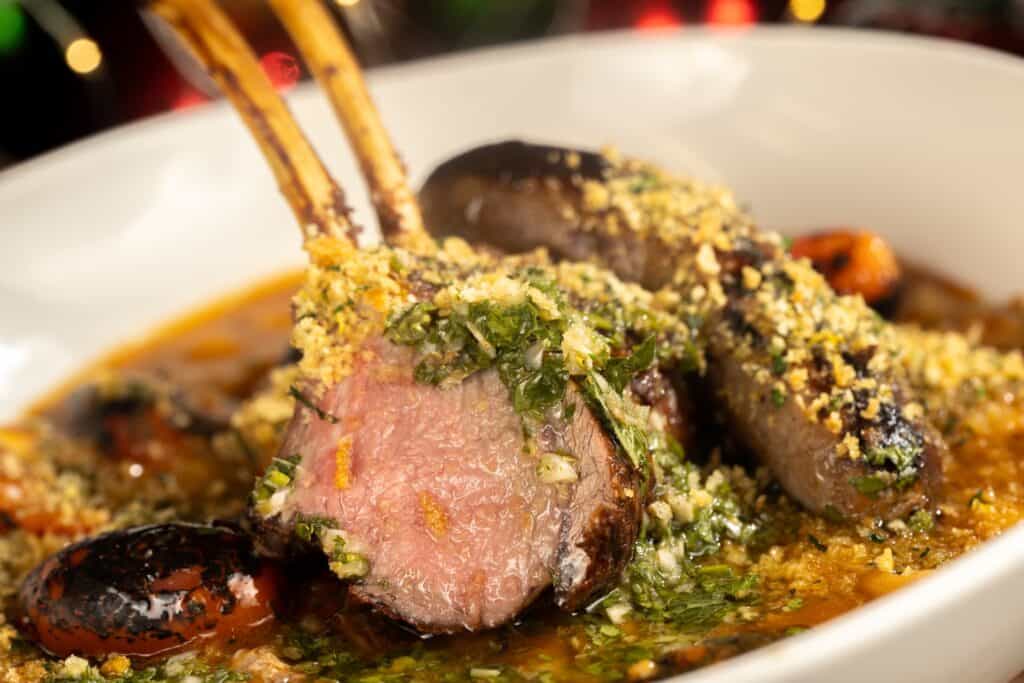 Succulent lamb chops with herb crust in a rich sauce, garnished with fresh herbs and crunchy bread crumbs.