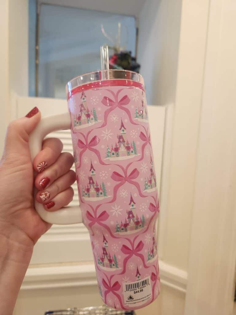 Pink Disney castle-themed tumbler with bows, snowflakes, and a straw.