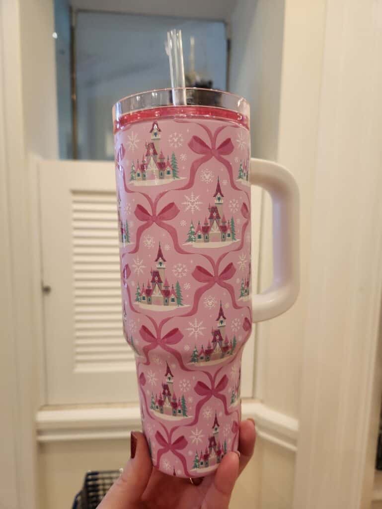 Pink Disney castle tumbler with bows and snowflakes, perfect for Disney fan gift or holiday decor.