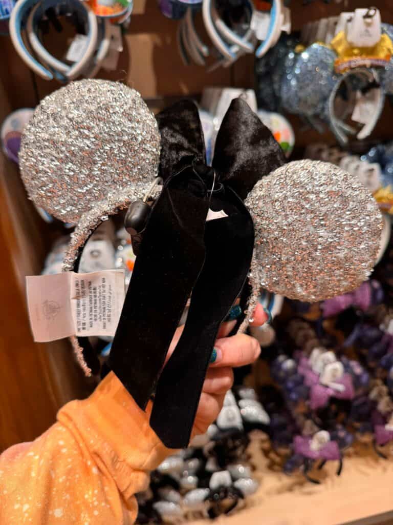 Sparkly Disney Minnie Mouse ears headband with glittering ears and black satin bow for Disney fans.