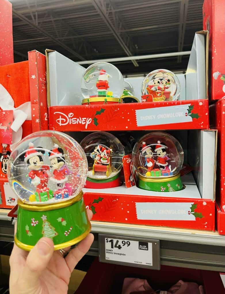 Christmas Disney snow globe with Mickey and Minnie Mouse in holiday outfits and festive scene.