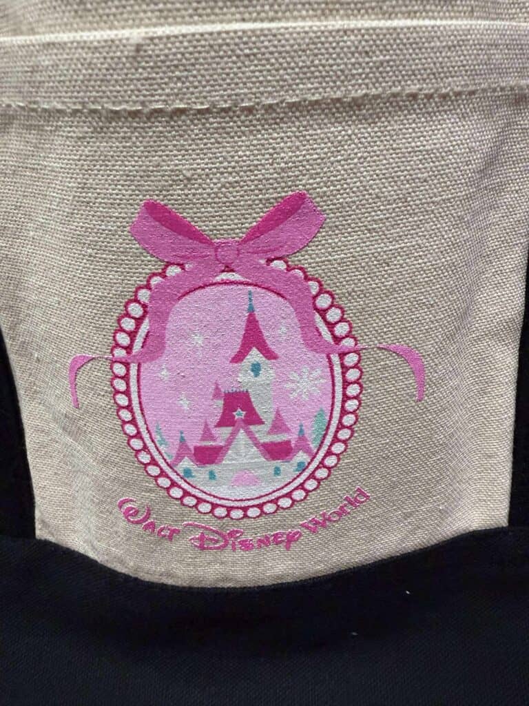 Colorful Disney Princess castle embroidery on a beige fabric backpack.