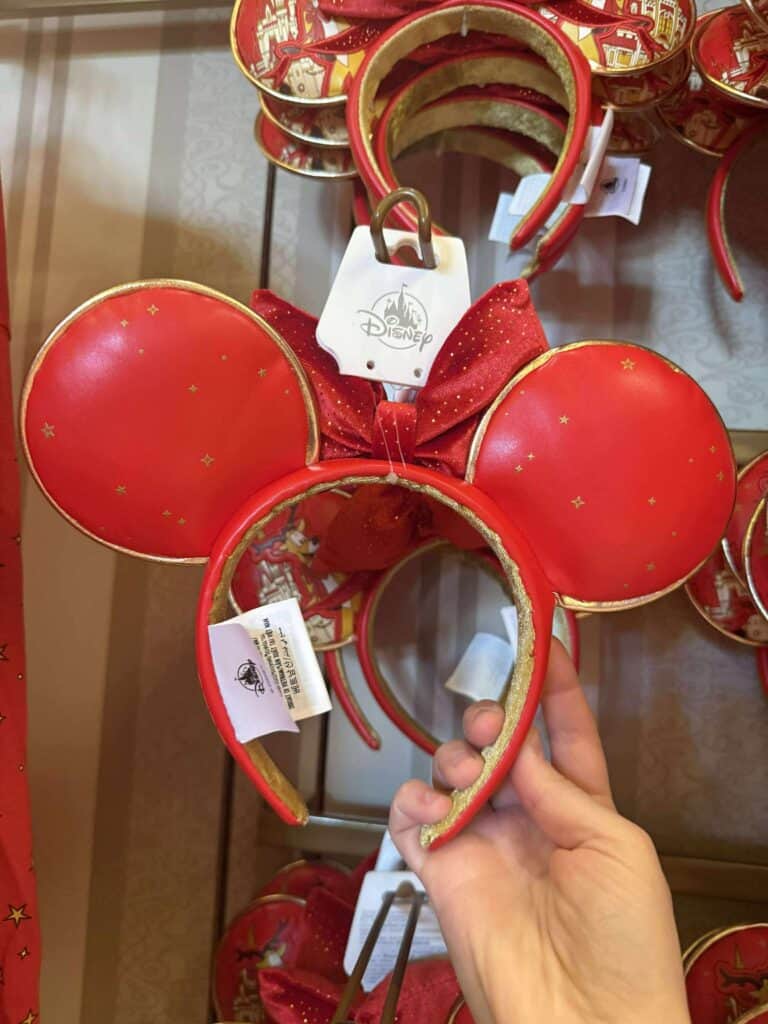 Disney Minnie Mouse ears headband with red bow and gold accents, perfect for Disney fans and theme park visitors.