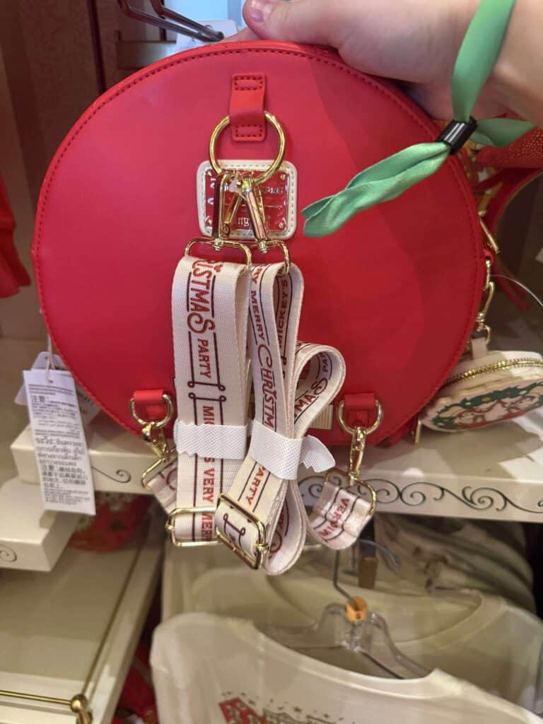 Red round Disney-themed handbag with gold hardware and Christmas-themed bag straps.